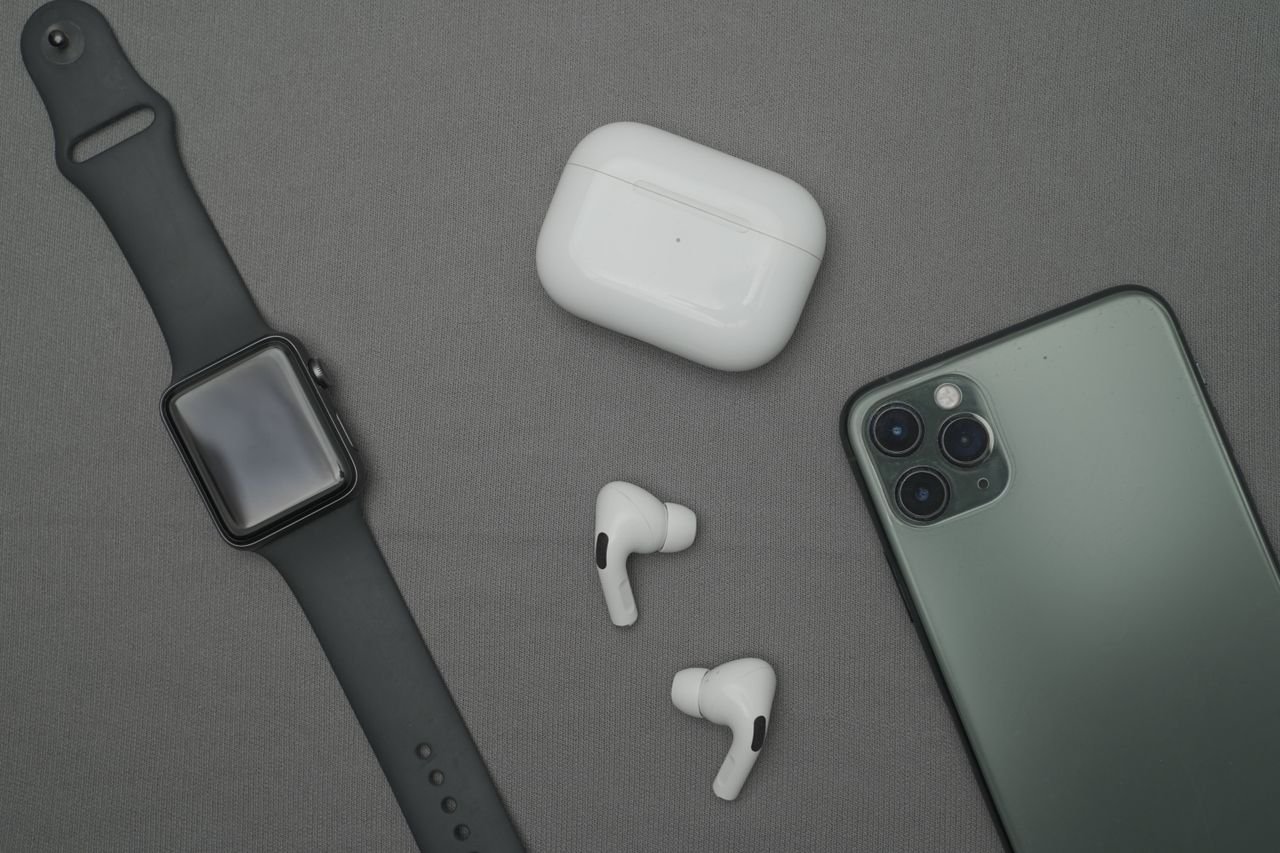 social-feed-img-01 Flat lay of smartwatch, smartphone, and wireless earbuds on a gray background.