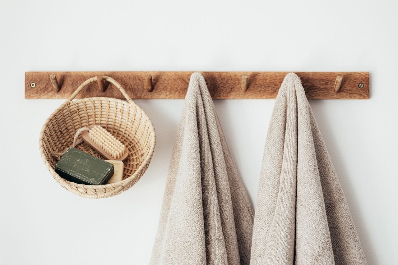 social-feed-img-02 Wooden wall hanger with soft towels and wicker basket with natural spa cosmetics products