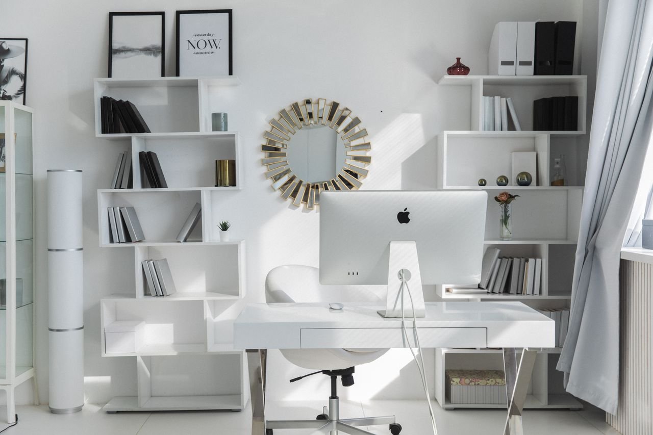 social-feed-img-04 Bright minimalist home office setup with white shelves, desk, and iMac. Ideal for productivity.